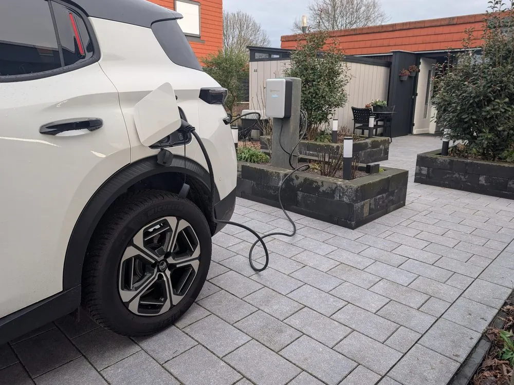 Elektrische auto die thuis laadt aan een laadpaal in de voortuin