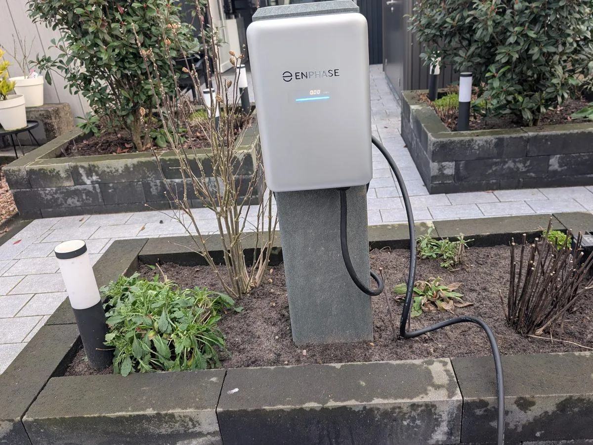 Laadpaal op een sokkel in een aangelegde voortuin